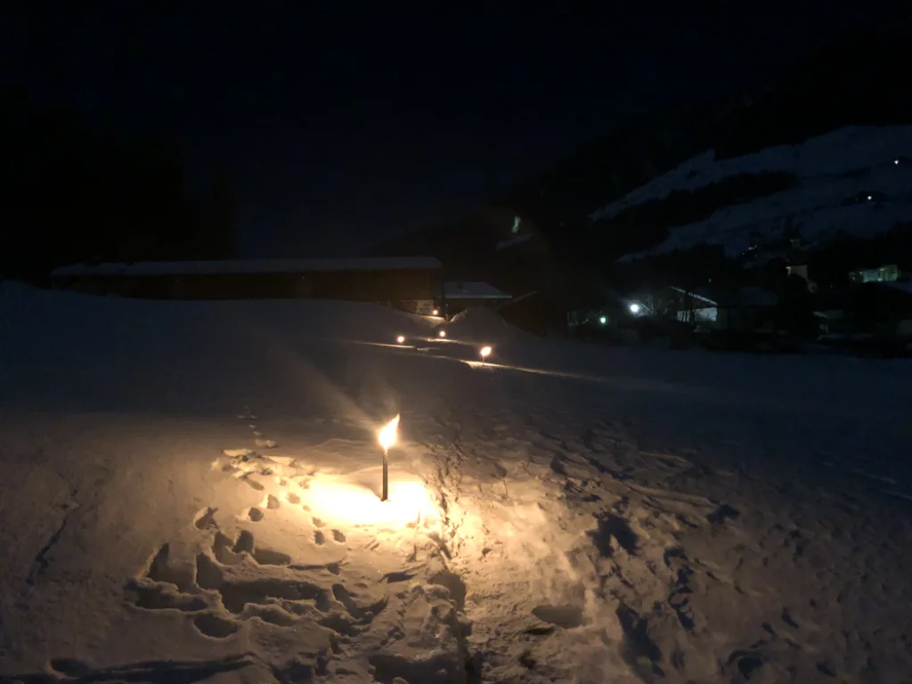Brennende Fackeln im Schnee bei Nacht.